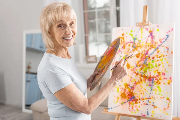 Happy mature woman finishing painting — Stock Photo, Image