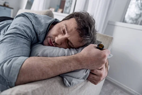 П'яний чоловік тримає пляшку, засинаючи на дивані — стокове фото