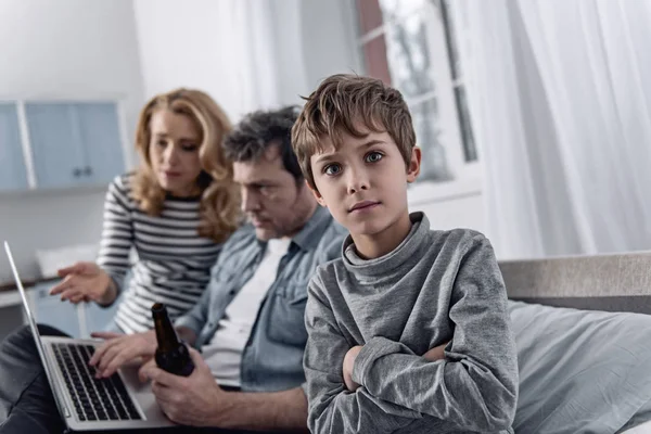 Garçon calme croisant les bras tout en étant assis avec des parents émotionnels — Photo