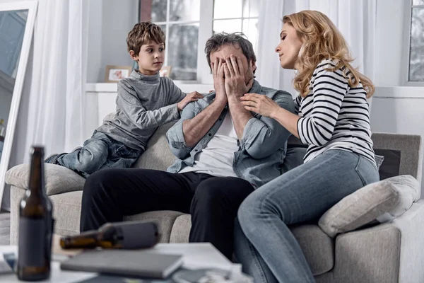 Alcoholische man verbergen van zijn gezicht tijdens een gesprek met zijn familieleden — Stockfoto