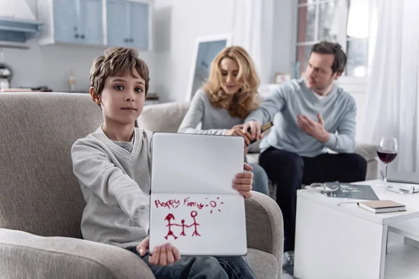 Оптимістичний хлопчик малює щасливу сім'ю, коли його батьки сваряться — стокове фото