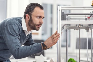 Ciddi genç mühendis konumlandırılması 3d printerlere harcama maddeler