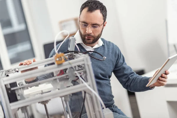 Ingeniero agradable en anteojos monitoreando el trabajo de la impresora 3D — Foto de Stock