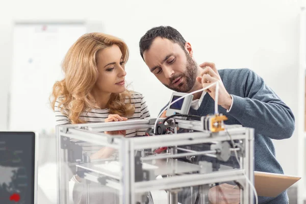 Agradable hombre enseñando a su colega cómo utilizar la impresora 3D —  Fotos de Stock