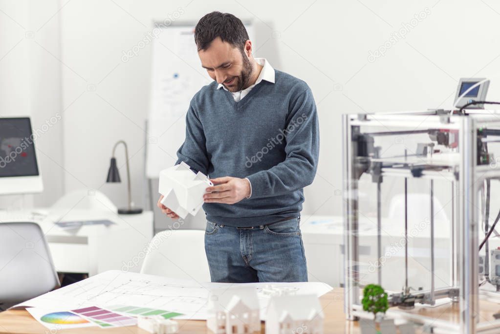 Upbeat engineer looking at the model of house