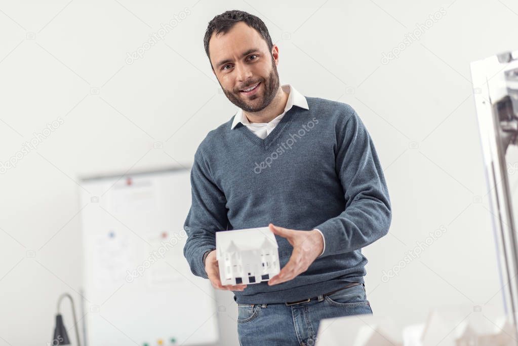 Cheerful young man showing a 3D model of house