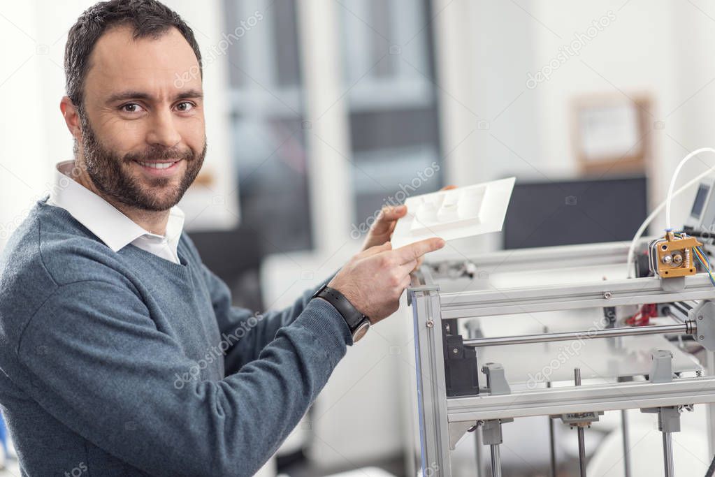 Cheerful engineer showing model printed with help of 3D printer