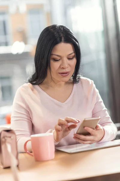 Serious nice woman looking at the smartphone screen — Stock Photo, Image