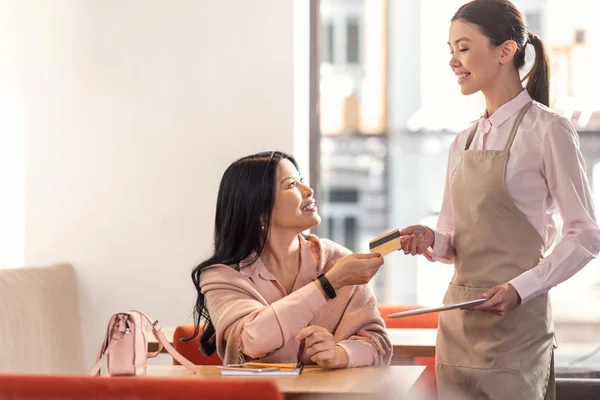 Blij leuke serveerster neemt een credit card — Stockfoto