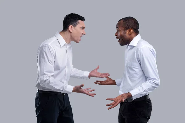 Homem irritado gritando com seu colega afro-americano — Fotografia de Stock