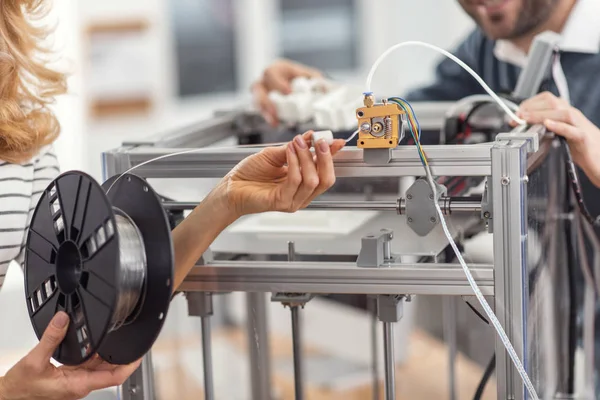 Manos femeninas sosteniendo filamento conectadas a extrusora de impresora 3D — Foto de Stock