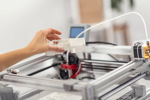 Vrouwelijke hand met het model van een huis boven de 3D-printer — Stockfoto