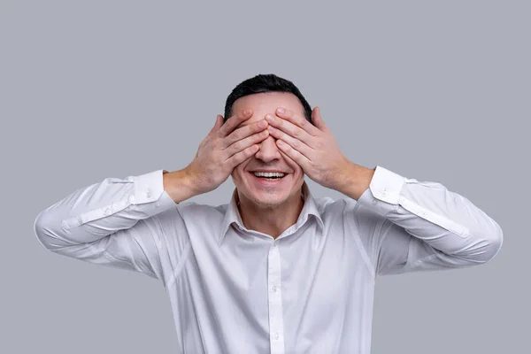 Smiling man closing his eyes with his hands — Stock Photo, Image
