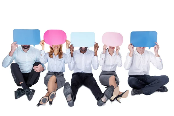 Smiling colleagues covering their faces with tables — Stock Photo, Image