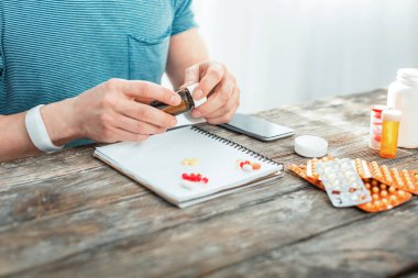 Oturan ve hapları çürüyen sorumlu özenli adam.