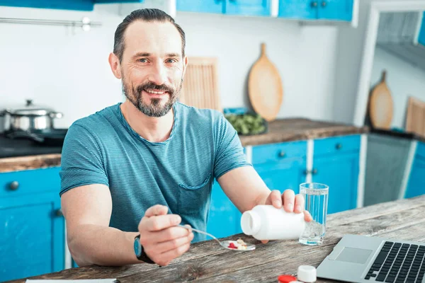 Satisfied beardful man holding a spoon and smiling. — Stock Photo, Image