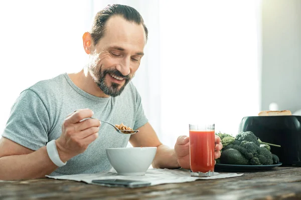 Tevreden beardful man glimlachend en eten van de vlokken. — Stockfoto