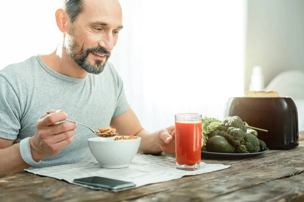 Roliga glada mannen äter flingor tar ett glas saft. — Stockfoto