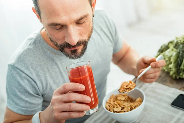 Handsome calm man eating and drinking juice. — Stock Photo, Image