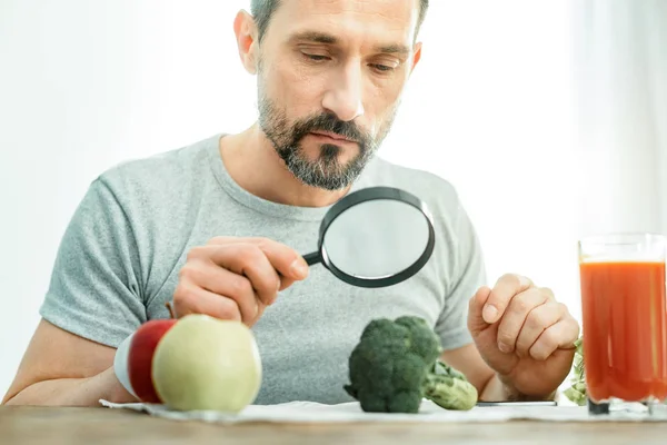 Serious curious man sitting and looking through the magnifying glass. — Stock Photo, Image