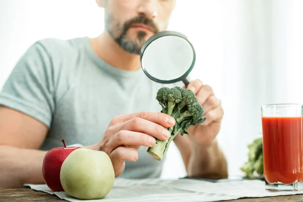 Attentive interested man holding and overlooking a broccoli. — Stock Photo, Image