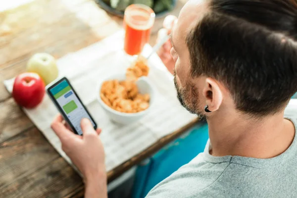 Ockuperade lugn man äter och använder hans mobiltelefon. — Stockfoto