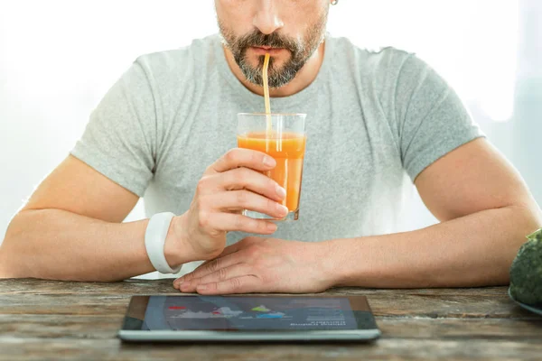Concentré homme agréable regardant le jus de boisson ordinateur portable . — Photo