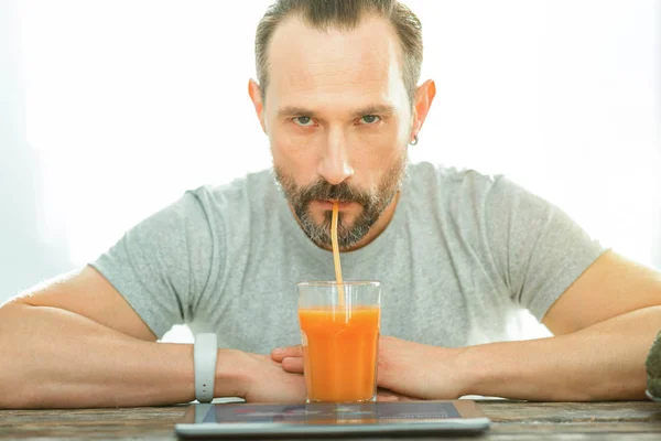 Serious unhappy man sitting and drinking juice. — Stock Photo, Image