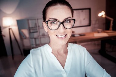 Gülümseyen ve düz seyir gözlüklü hoş kadın.