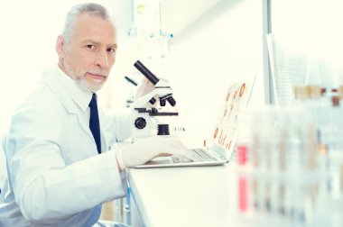 Mikroskop ve dizüstü bilgisayar üzerinde çalışan ciddi araştırmacı