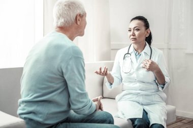 Oturma ve hasta için tavsiyeler vererek şirin deneyimli hemşire.