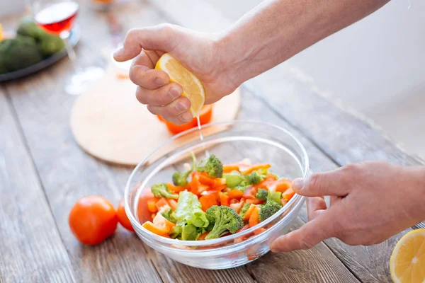 Mãos masculinas temperando salada vegetal — Fotografia de Stock