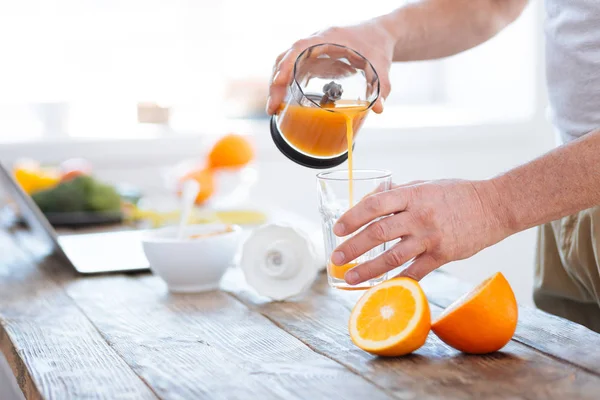 Mãos jovens masculinas derramando suco de laranja — Fotografia de Stock
