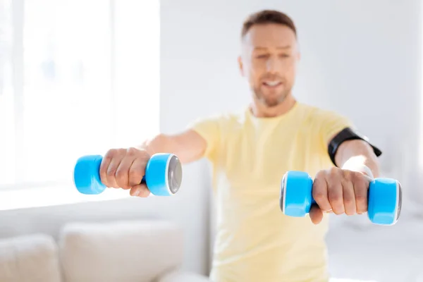 Concentrated man rising dumbbells — Stock Photo, Image