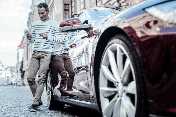 Homme joyeux positif appuyé sur sa voiture — Photo