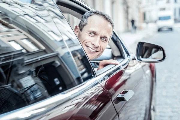 Hombre alegre positivo mirando por la ventana del coche — Foto de Stock