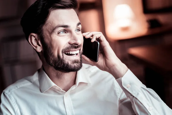 Happy pleasant man smiling and having phone conversation. — Stock Photo, Image