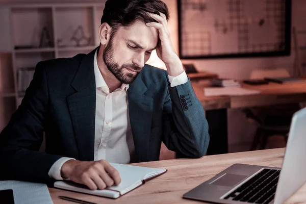 Verärgerter tiefer Mann stützt seinen Kopf am Tisch. — Stockfoto