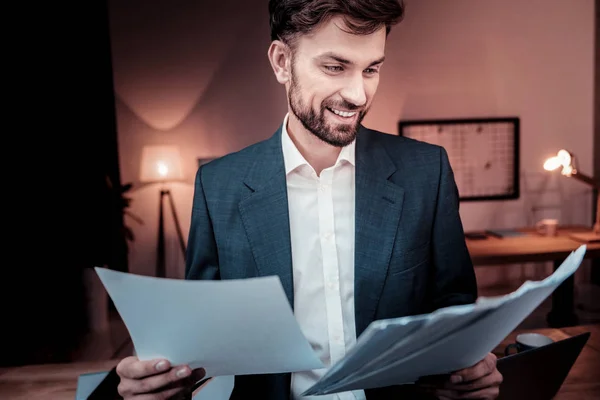 Ansvarig skickliga medarbetare leende och med utsikt över dokument. — Stockfoto