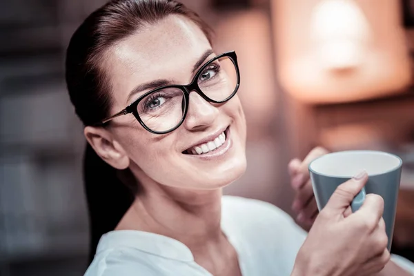 Linda mujer con gafas sonriendo y bebiendo té . — Foto de Stock