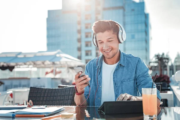 Positiva sinnade ung man lyssnar på musik i café — Stockfoto