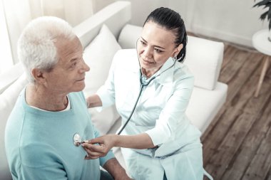 Şirin deneyimli hemşire hastasını muayene ve oturma.