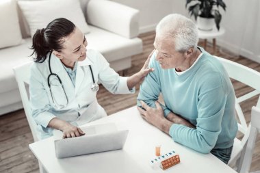 Neşeli keyifli hemşire hastasını yatıştırıcı ve oturma.