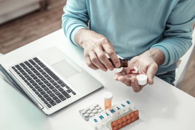 Kıdemli oturma ve hapları el dökülen adam yaşlı.