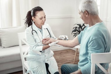 Hastaların kol tutarak ve enjeksiyon yapma sakin ciddi hemşire.