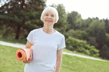 Bir yoga mat tutan mutluluk pozitif kadın