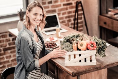Sebze ile belgili tanımlık kutu önüne oturan olumlu güzel kadın