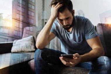 Kızgın genç adam onun smartphone ile otururken düşünceli arıyorum