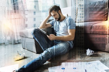 Serious man sitting on the floor and feeling tired of work clipart