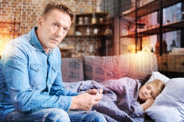 Endişeli baba oğlu koltukta istirahat ederken bir termometre holding